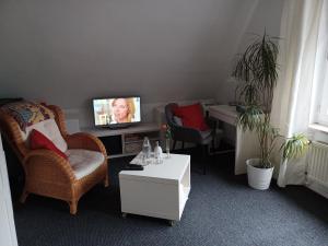 ein Wohnzimmer mit einem TV, einem Stuhl und einem Tisch in der Unterkunft Familienzimmer HH-Schnelsen in Hamburg