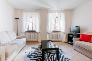 a living room with a couch and a tv at Sartori Mountain Apartment in Pinzolo