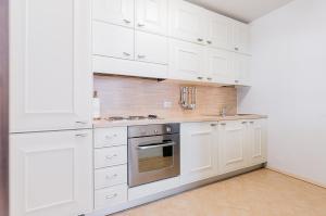 a white kitchen with white cabinets and a stove at Sartori Mountain Apartment in Pinzolo +9 photos
