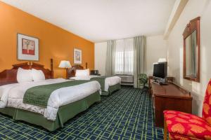 a hotel room with two beds and a television at Baymont by Wyndham Greensburg in Greensburg