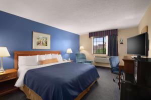 a hotel room with a bed and a flat screen tv at Days Inn by Wyndham Keene NH in Keene