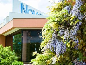 マコンにあるNovotel Macon Nord Autoroute du Soleilの紫色の花束が咲き誇る建物