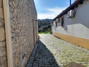 an alley between two buildings with a stone wall at Vilas da Matagosa in Matagosinha