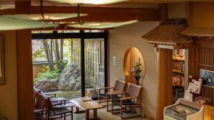 Habitación con sillas, mesas y una ventana grande. en Kashintei Shirahama, en Senboku