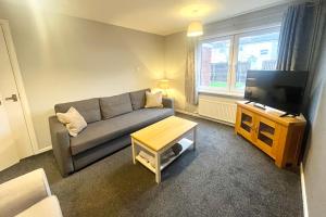 a living room with a couch and a television at Spacious 2 double bed city home in Hereford