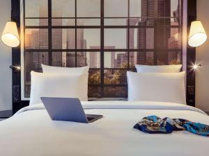 un computer portatile su un letto con vista sulla città di Mercure Paris la Défense Grande Arche a Nanterre