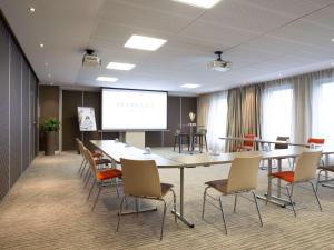a conference room with a table and chairs and a screen at Mercure Clermont Ferrand centre Jaude in Clermont-Ferrand