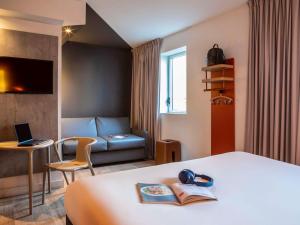 a hotel room with a bed and a couch at ibis budget Paris Clichy Mairie in Clichy