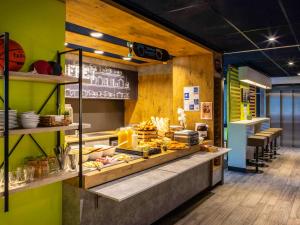 a restaurant with green walls and a counter with food at ibis budget Paris Clichy Mairie in Clichy
