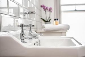 een witte wastafel met een kraan in de badkamer bij The Cosy Cottage in Litcham +10 foto's