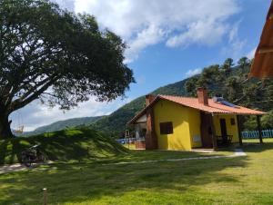 ein gelbes Haus mit einem Berg im Hintergrund in der Unterkunft Chalé Mirante Da Guapiara in Aiuruoca
