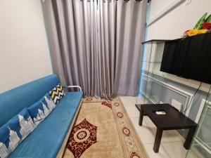 een woonkamer met een blauwe bank en een tafel bij Homestay Epoh Meru Raya F3 with Netflix in Ipoh