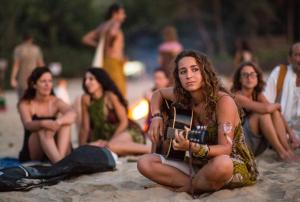 un grupo de personas sentadas en la playa en Borrbo Beach Hostel Gokarna, en Gokarna