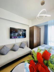 a living room with a couch and a tv on the wall at City View Studio Unit at Centrio Tower beside Ayala Mall in Cagayan de Oro