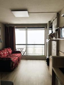 a living room with a couch and a large window at Studio refait à neuf avec balcon Ouest Résidence Le Galaxie in Villard-de-Lans