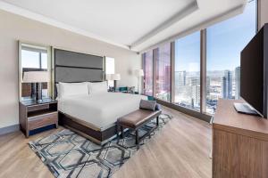 a bedroom with a bed and a desk and windows at Hilton Club Elara Las Vegas in Las Vegas