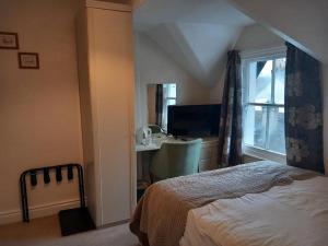 a bedroom with a bed and a desk and a window at Silverdale Guesthouse in Keswick