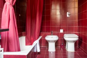 y baño rojo con aseo, bañera y lavamanos. en L'eco della rosa en Crema