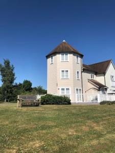 a large white house with a fence and a yard at Stunning New England Style Lakeside Lodge in Cirencester