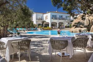 una mesa junto a la piscina en un complejo en Hotel La Rocca Resort & Spa, en Baja Sardinia