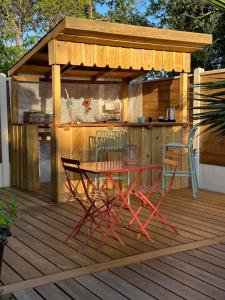 een tafel en stoelen op een houten terras met een schuur bij Chez Karine & Eric in Le Teich