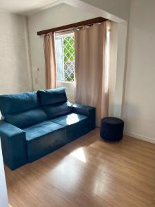 ein blaues Sofa im Wohnzimmer mit Fenster in der Unterkunft Casa aconchegante em São Gabriel in São Gabriel