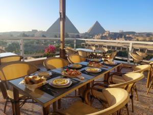 開羅的住宿－DouDou Pyramids View Hotel，一张桌子,上面有金字塔背景的食物