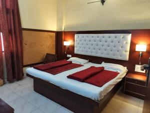 a bedroom with a large bed with two red pillows at Hotel Prince Palace (The Green) in New Delhi