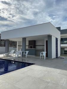 a white building with chairs and a swimming pool at Apt. Ah-Mar in Porto Seguro