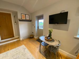 a living room with a table and a tv on the wall at The Annexe in Middleham