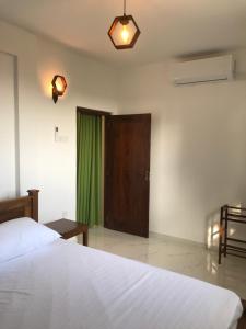 a bedroom with a bed and a door with a green curtain at Star Beach Villa in Tangalle