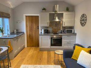 a kitchen with white cabinets and a blue couch at The Annexe in Middleham