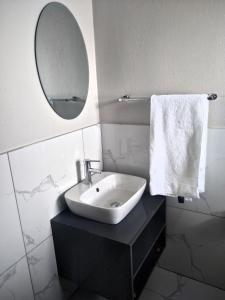a white bathroom with a sink and a mirror at Thomsons Lodge in Polokwane
