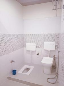 a white bathroom with a toilet and a sink at The Royal Sahdeo Venue in Gaya