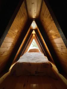 uma cama num sótão de madeira com uma janela em Liki Home em Lerik