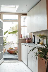 a kitchen with white cabinets and a large window at Boutique Beach Retreat in Westward Ho