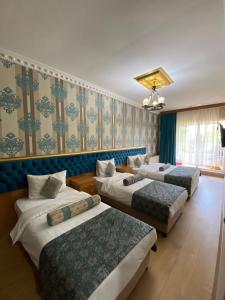 três camas num quarto com papel de parede azul e verde em GOLDEN PALACE SEA ViEW em Istambul