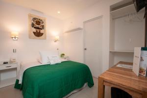 Un dormitorio con una cama verde y una mesa en Hotel Riviera Inka Paracas en Paracas