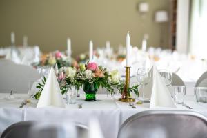 Villa Puharila في Längelmäki: طاولة مع طاولات بيضاء مع الزهور والشموع