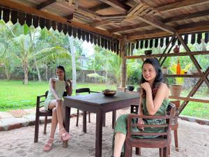 Deux femmes assises à une table dans un pavillon dans l'établissement Ananda Marari Heritage Villa, à Alappuzha