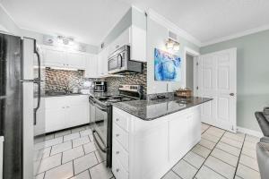 a kitchen with white cabinets and a black refrigerator at The Summit 1426 in Panama City Beach