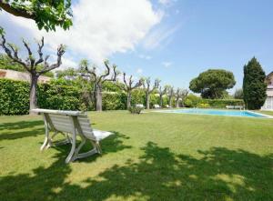 a bench sitting in the grass near a swimming pool at Apartamento Duplex Voramar in S'agaro