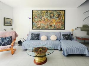 a living room with a couch and a painting on the wall at Apartamento Duplex Voramar in S'agaro +25 photos