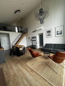 sala de estar con sofá y sillas y escalera en Modernūs apartamentai Svencelėje, en Svencelė