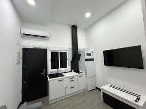 uma cozinha com armários brancos e uma televisão de ecrã plano em Cotrades 3 En San Blas-Canillejas em Madri