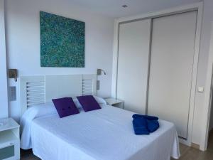 una camera da letto con un letto bianco con cuscini viola di Vivienda vacacional “Punta de la arena” a Breña Baja