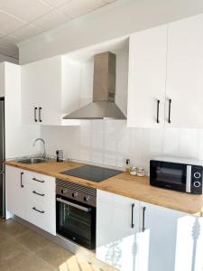 een keuken met witte kasten, een wastafel en een magnetron bij Casa Primavera in Zurgena