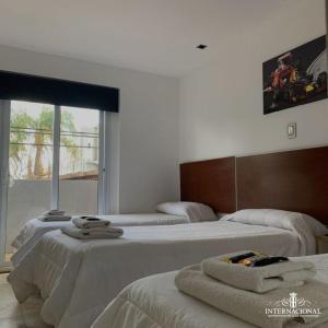 Habitación con 3 camas y toallas. en Hotel internacional en Termas de Río Hondo