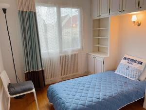 - une chambre avec un lit bleu et une fenêtre dans l'établissement Villa Seine, à Bezons