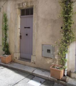 una porta sul lato di un edificio con due piante di Longo Mai ad Apt